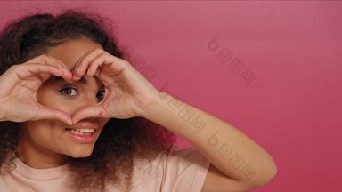 爱心手势美丽的年轻的非洲美国女人微笑积极相机穿桃色的t恤孤立的粉红色的背景爱概念镜头